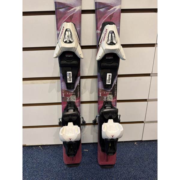 Skis enfant Atomic Maven Girl avec fixations Atomic C5 GW, gros plan sur le milieu de skis rose et violet, longueur 70, devant un mur